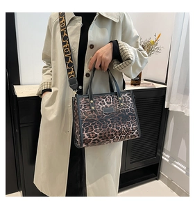 Detail of leopard print tote bag with black leather trim and branded wide shoulder strap