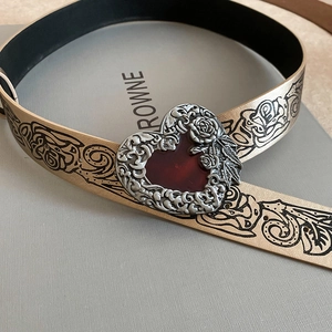 Macro detail of gothic gold belt featuring black rose patterns and silver heart buckle