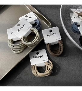 Close-up of earth-toned elastic hair bands set on a minimalist textured background