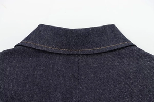 Detailed macro view of denim collar with orange contrast stitching on dark blue fabric