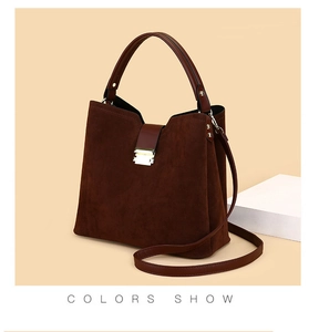 Detail of dark brown suede handbag with leather handles and gold metal buckle