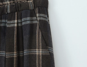 Detail of plaid trousers showing elastic waistband, side pockets and woven fabric texture