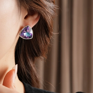 Gros plan d'une boucle d'oreille géométrique en strass violet sur une monture argent