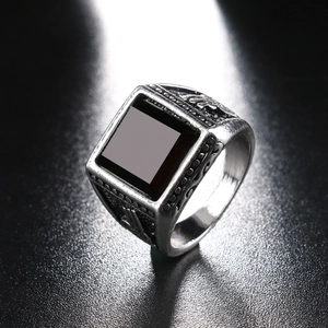 Men's vintage silver ring with a square black stone set on a textured dark background