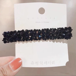 Detail view of handmade black crystal beaded rectangular hair clip on a display card