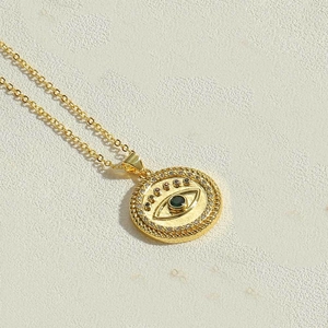 Detailed macro view of gold evil eye pendant necklace with green gemstone and small zircons