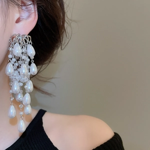 Detailed view of layered silver tassel earrings with cascading white pearls and metal chains