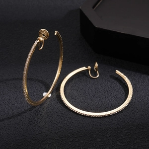 Close-up of golden clip-on hoop earrings with sparkling crystal rhinestones set in metal