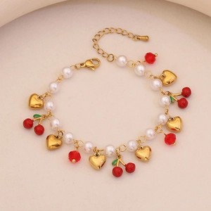Detail of cute cherry and strawberry charm bracelet with pearls and golden hearts