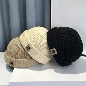 Detalle de textura de punto de gorros de otoño e invierno en crema, marrón y negro con parche R