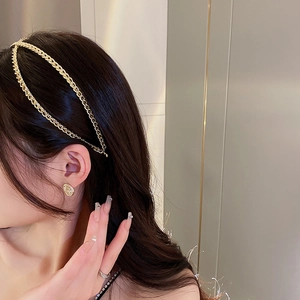 Détail d'un serre-tête à double chaîne dorée et boucles d'oreilles assorties sur un modèle