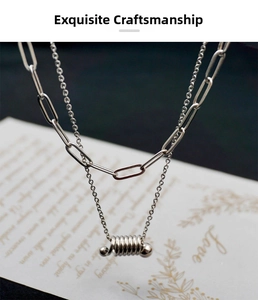 Detail view of double-layered silver necklace with paperclip chain and coil pendant