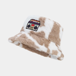 Close-up of fluffy faux fur bucket hat with cow print and retro radio patch detail