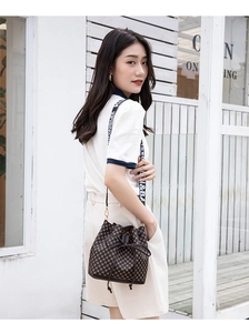 Detailed view of dark brown bucket bag featuring monogram pattern and wide logo strap
