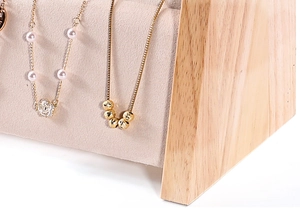 Close-up of wooden jewelry display stand with beige velvet lining for large necklaces