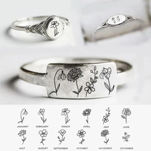 Macro detail of 925 sterling silver birth flower rings with engraved floral patterns