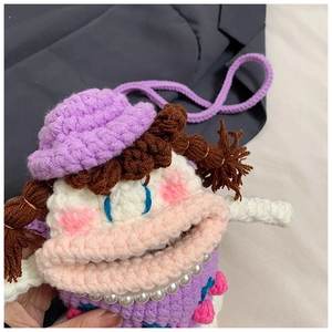 Detail showing handmade crochet sausage mouth bag with purple hat and pearl necklace