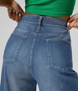 Dettaglio dei jeans a vita alta con focus sulle tasche posteriori e trama denim