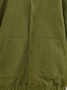Close-up detail of olive green textured fleece jacket with large utility patch pockets