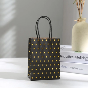 Detail of black paper gift bag with gold foil polka dots and black rope handles