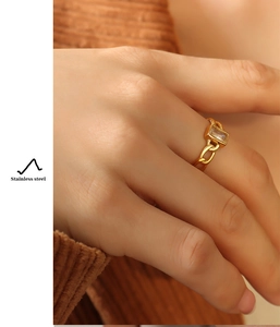 Close-up of gold stainless steel ring with green zircon and cuban chain on hand