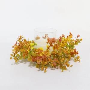 Macro shot of orange eucalyptus leaf candle ring with clear glass holder and white wax