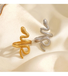 Close-up of gold and silver snake rings with scale texture on beige silk fabric