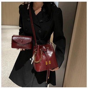 Détail du sac seau bordeaux brillant avec chaîne dorée et pendentif boule n°8