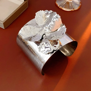 Macro detail of silver floral cuff bracelet showing hammered metal texture and petal design