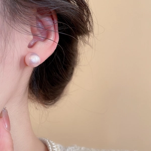 Detailed view of pink pearl stud earring with elegant luster on a model ear