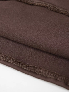 Close-up macro view of deep brown fabric showing detailed texture and woven pattern of the T-shirt
