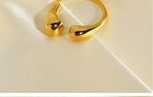 Bague ajustable dorée polie posée sur un tissu en soie crème aux reflets doux