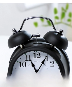 Detail view of black vintage metal twin bell alarm clock with chrome handle and hammer