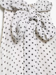 Detailed view of the white polka dot fabric and elegant decorative bow tie on the dress