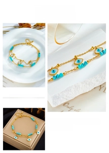 Detail of double-layered gold anklet with star, evil eye charms and turquoise beads