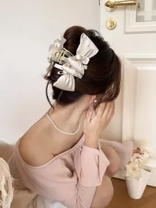 Close-up of cream silk bow hair claw clip worn by a model for an elegant hairstyle