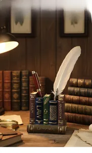 Detail view of vintage resin book-shaped pen holder with feather pen and antique decor