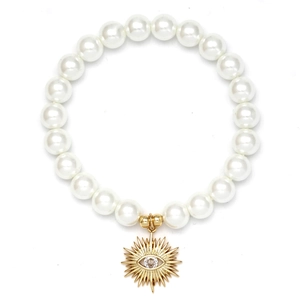 Detailed macro of white shell pearl bracelet with gold evil eye charm and clear crystal