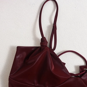 Macro shot of burgundy PU corset showing shoulder strap knot and metal eyelet details