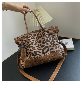 Detail of leopard print handbag with brown leather trim, fringe tassel, and bottom studs