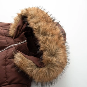 Close-up of fluffy faux fur collar and silver zipper on a brown quilted winter coat
