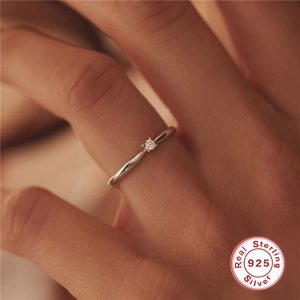 Close-up of a minimalist 925 sterling silver ring with a round diamond on a hand