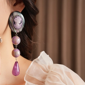 Macro detail of a vintage resin portrait teardrop earring with purple cameo and metal beads
