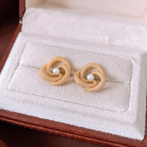 Macro detail of vintage gold textured knot earrings with center pearl in a jewelry box