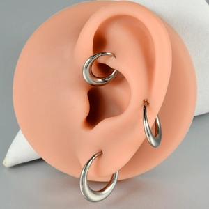 Polished silver G23 titanium hoop earrings shown on a silicone ear model piercing set