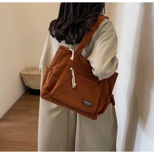 Close-up of brown corduroy tote bag showing side pocket and zipper with white knot puller