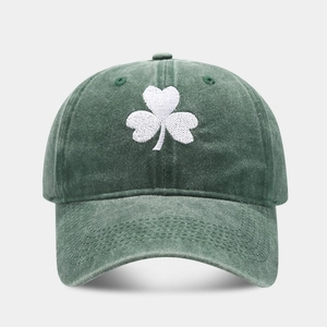 Close-up of white clover embroidery on a vintage washed green cotton dad hat