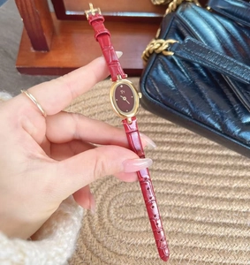 Detailed close-up of a red crocodile-texture leather strap watch with gold oval case