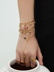 Détail d'un bracelet doré multi-rangs avec pendentifs coccinelle rouge et clochette