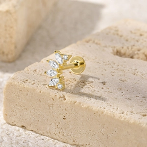 Macro shot of gold threaded labret stud with marquise crystals on beige stone base